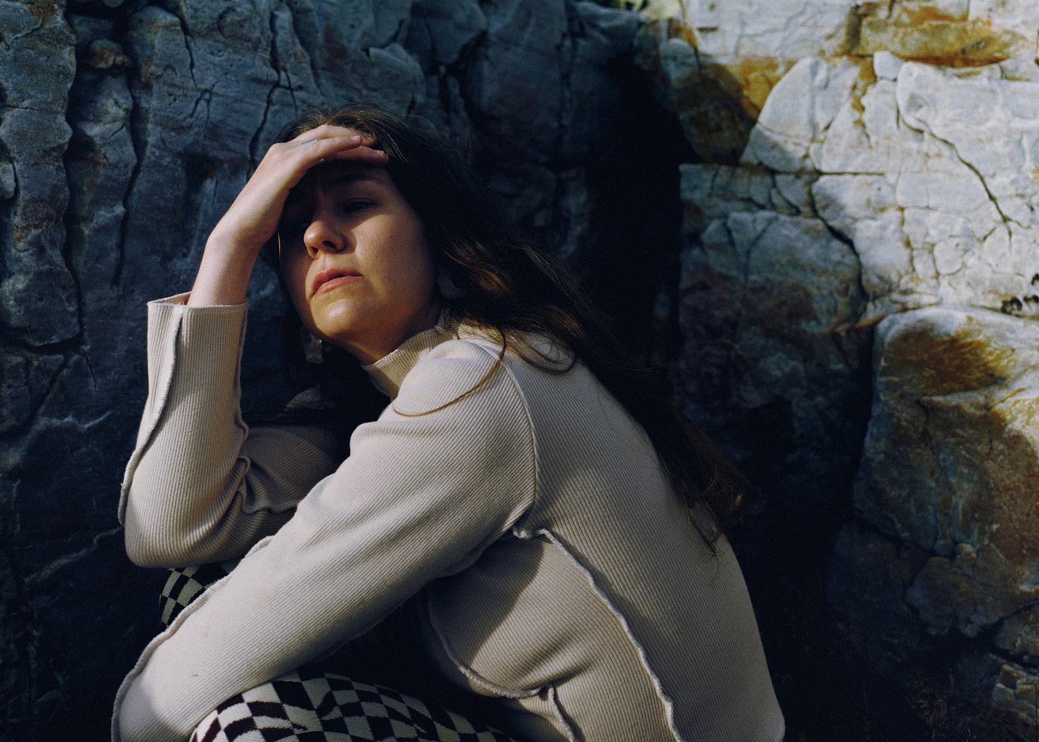 Alice Boman shielding her eyes from the sun against a background of grey rocks