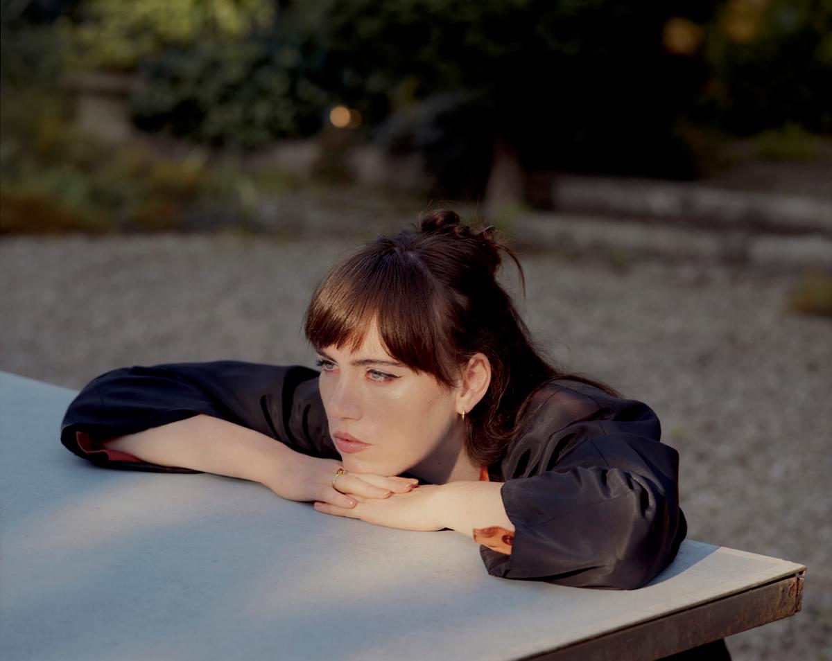 Aoife Nessa Frances resting her head on her hands leaning on a table for "This Still Life" single