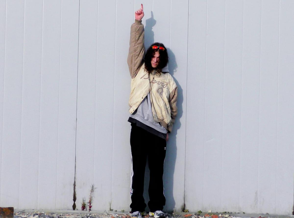 Bladee pointing upwards against a wall for "DRAIN STORY" single