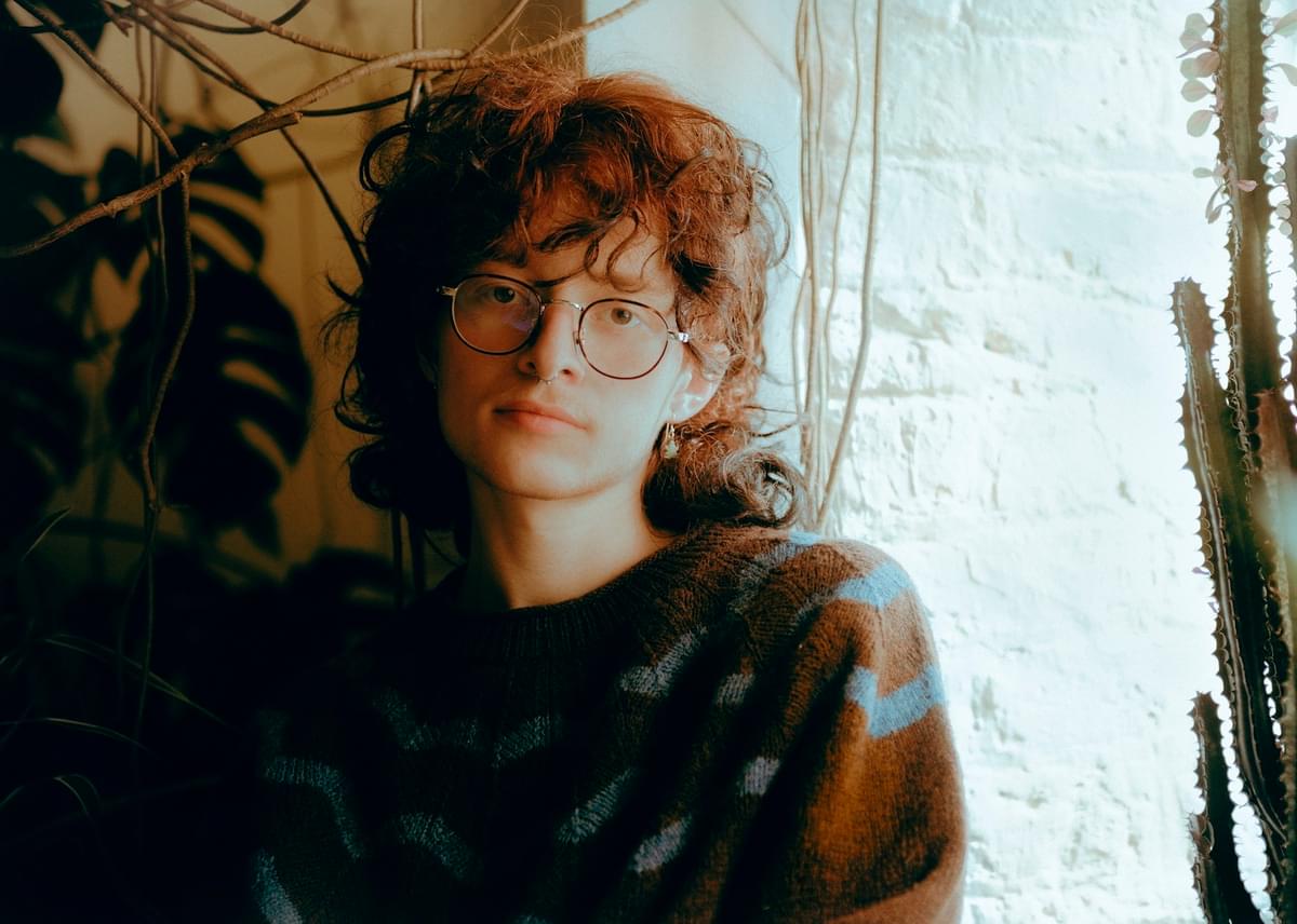 Cavetown sat near window with plants for worm food album announcement