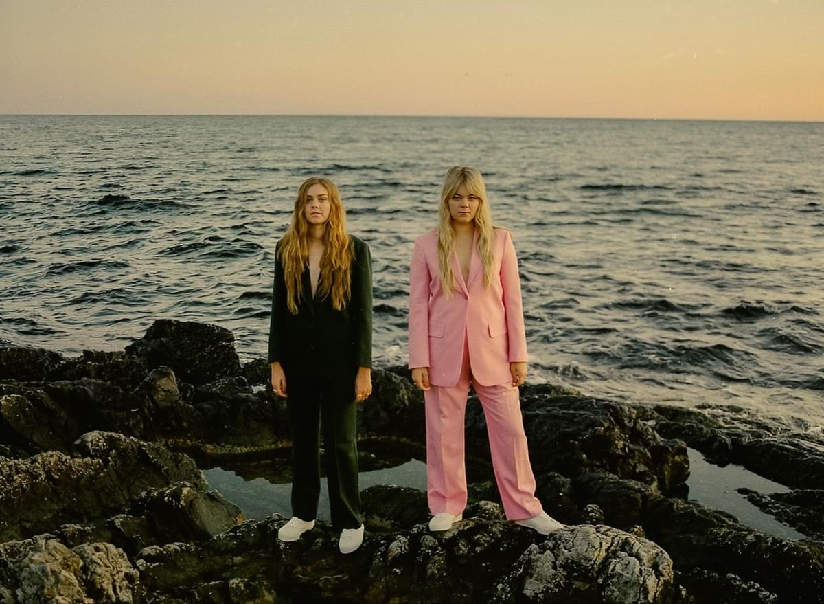 First Aid Kit wearing suits standinng on rocks at edge of sea