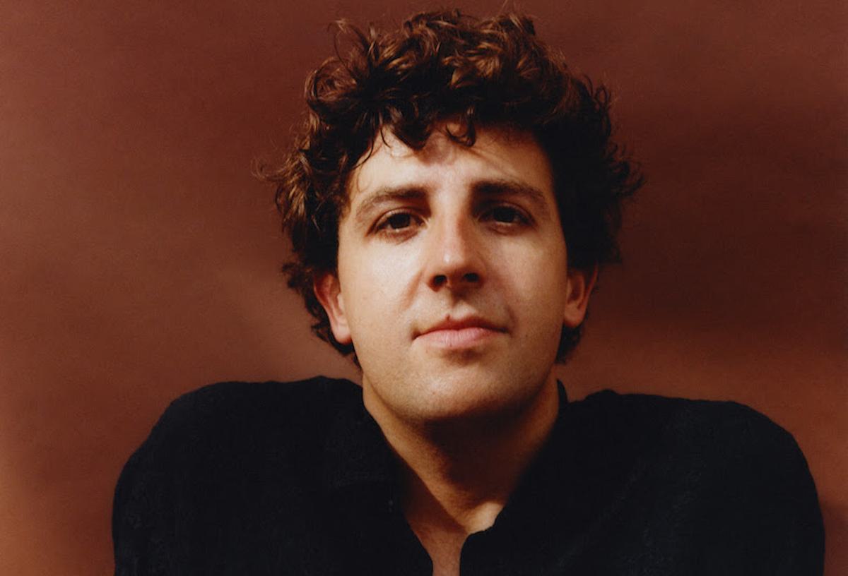 Jamie xx smiling against brown backdrop for "Kill Dem" single