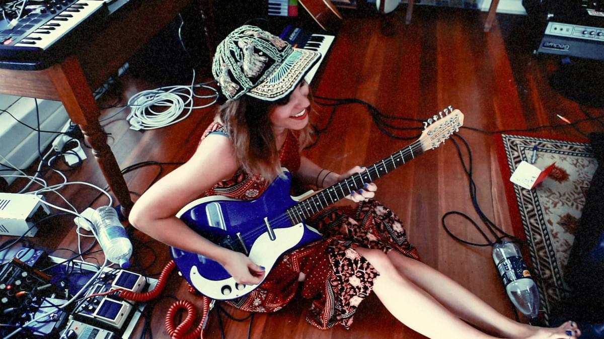 Melody's Echo Chamber playing guitar on the floor