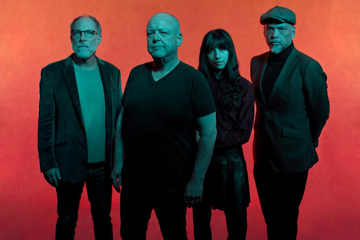 Pixies stood in front of an orange and red ombre backdrop