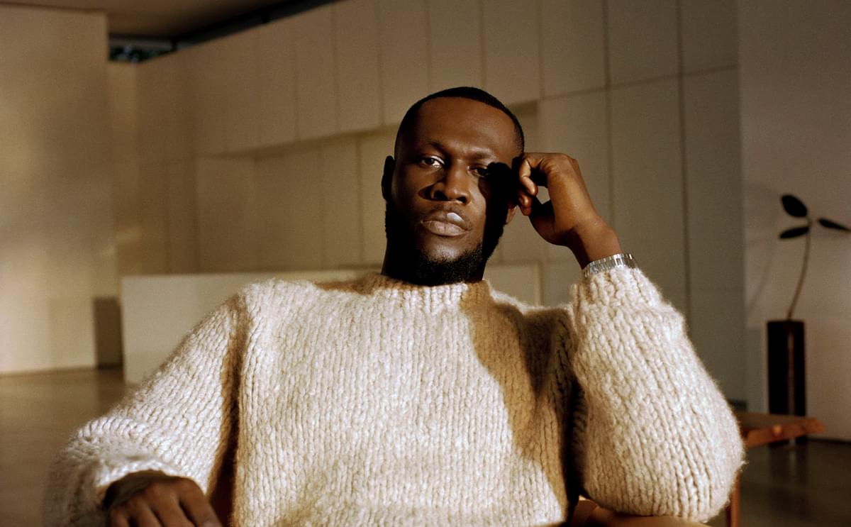 Stormzy beige siting in chair resting hand on face