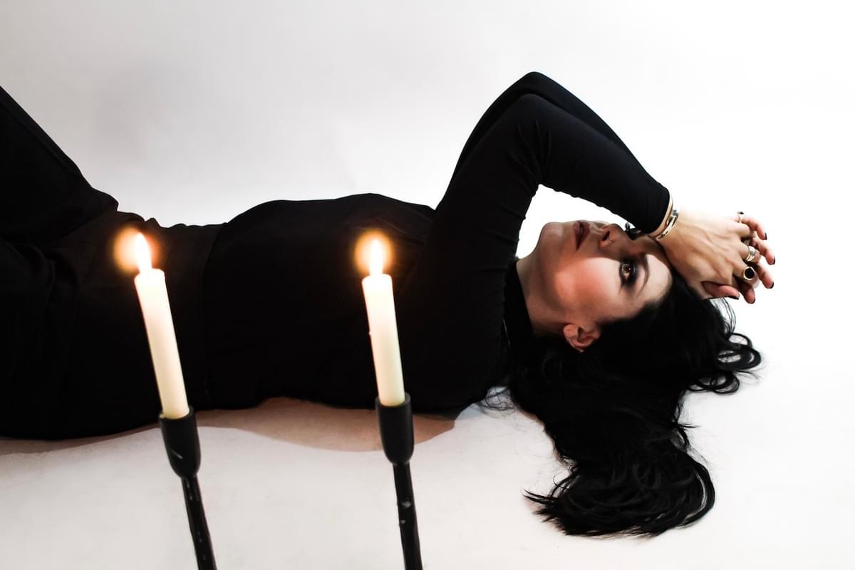 A.A. Williams lying on back next to candles for "The Echo" single